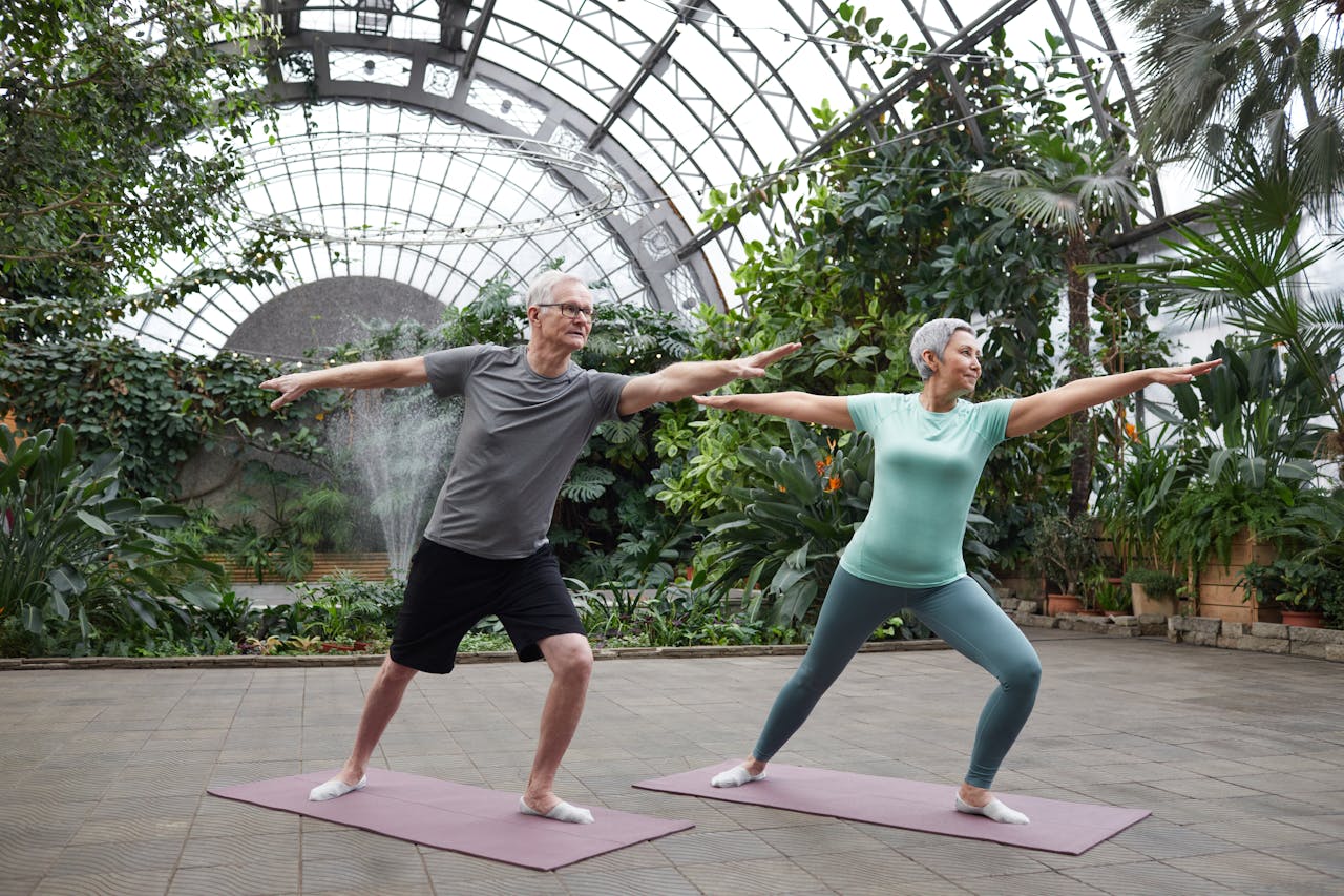 An older couple enjoys yoga in nature, representing the vibrant results of lymphatic massage therapy.