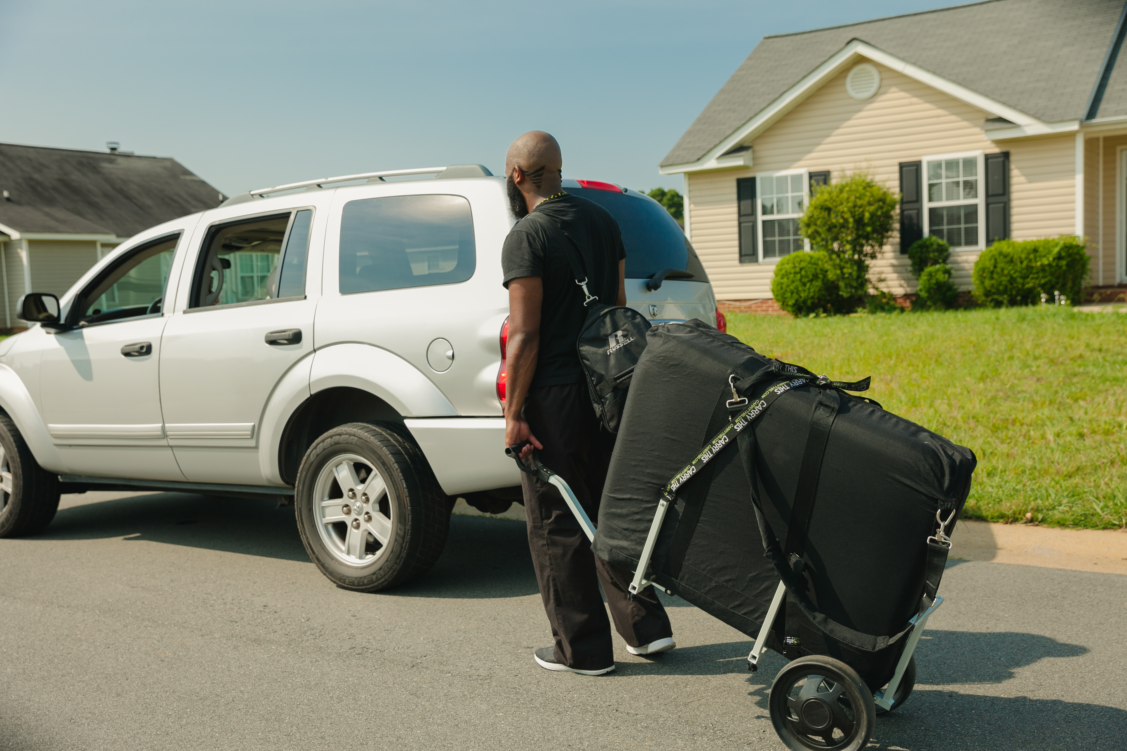 A massage therapist traveling to a mobile massage session with a professional massage bag and portable table.