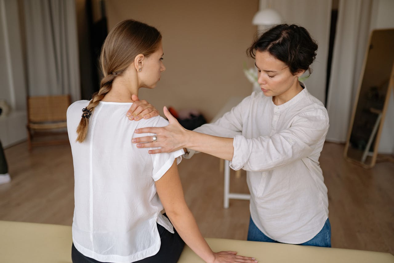 Close-up of a massage therapist applying precise, sustained pressure to a trigger point during neuromuscular therapy.
