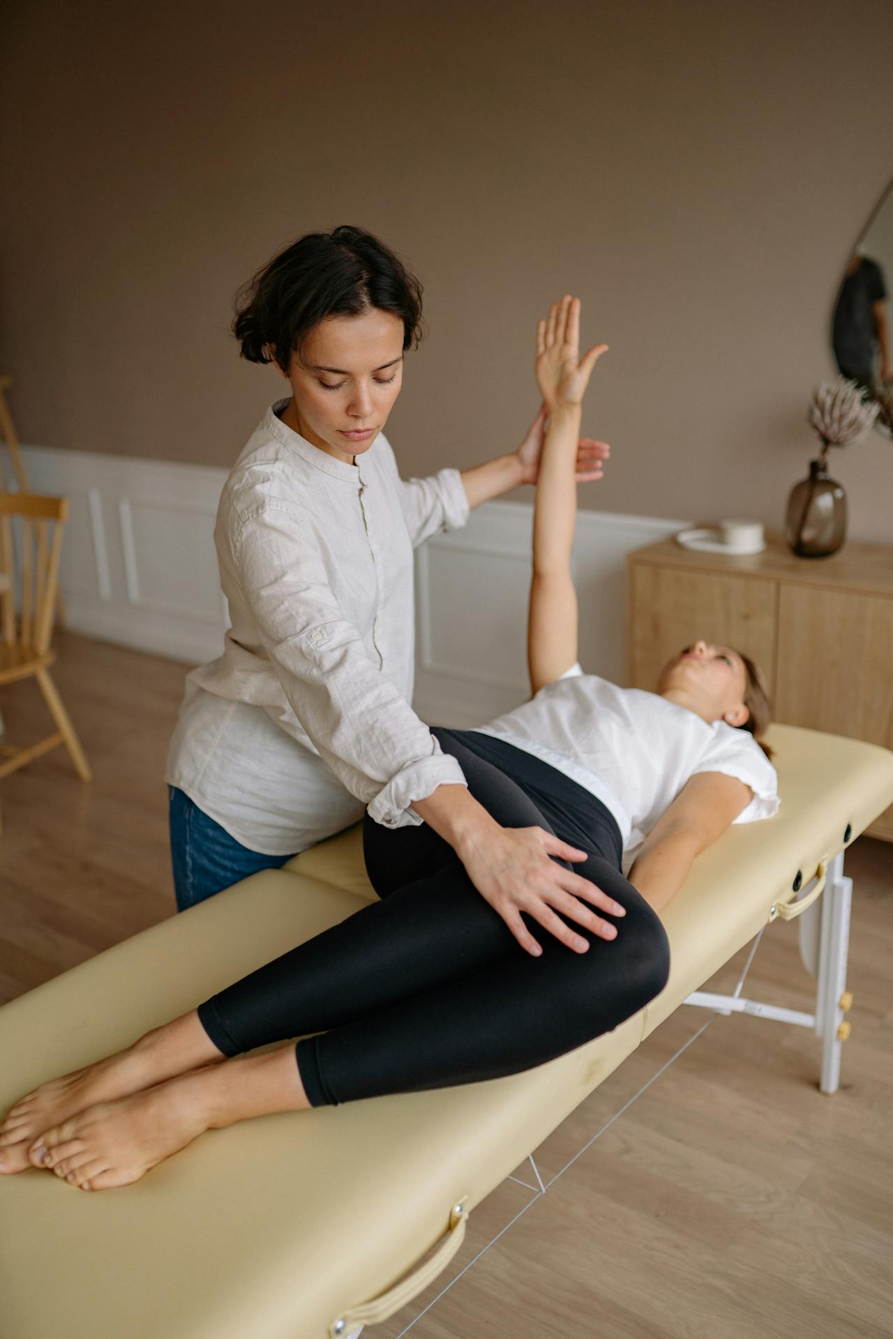 Massage therapist performing steps of the PNF stretching technique to a client.