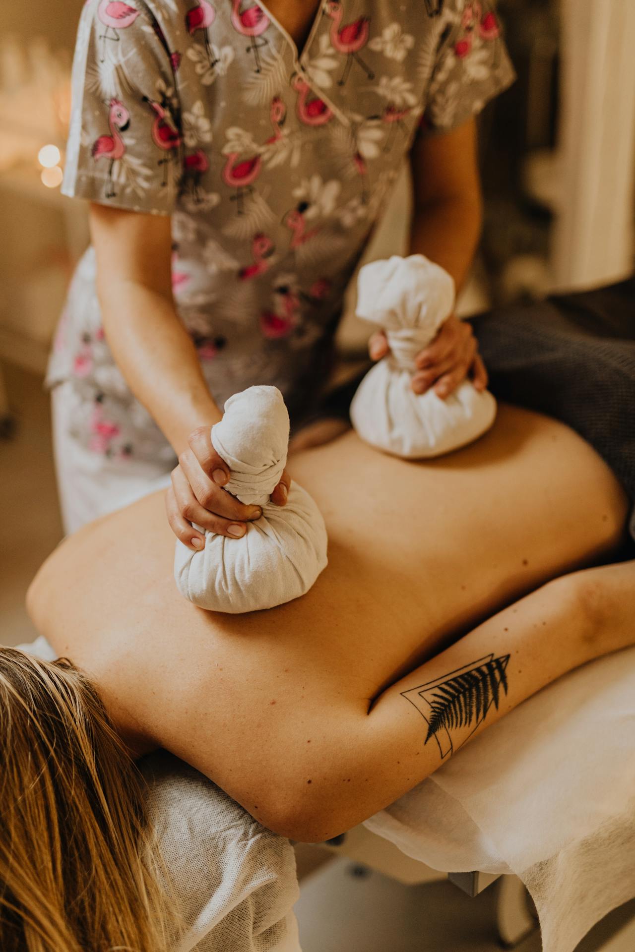 A licensed massage therapist applying cold packs to a client&rsquo;s back during cryotherapy treatment.