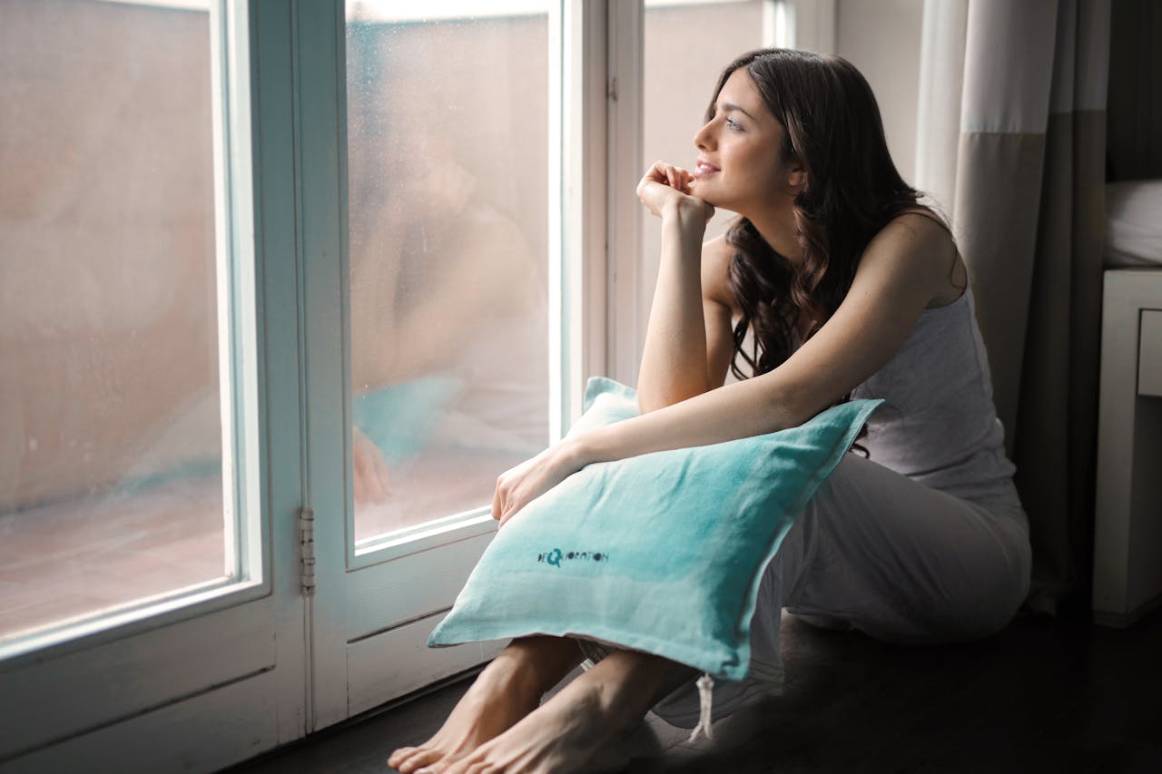 A person sits peacefully with a pillow, embodying a sense of safety and connection to themselves after trauma therapy.